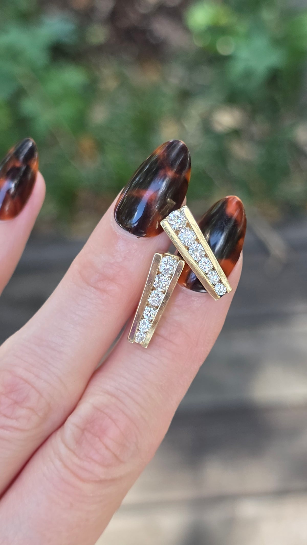 Gold ring with gemstones on a finger against a blurred natural background