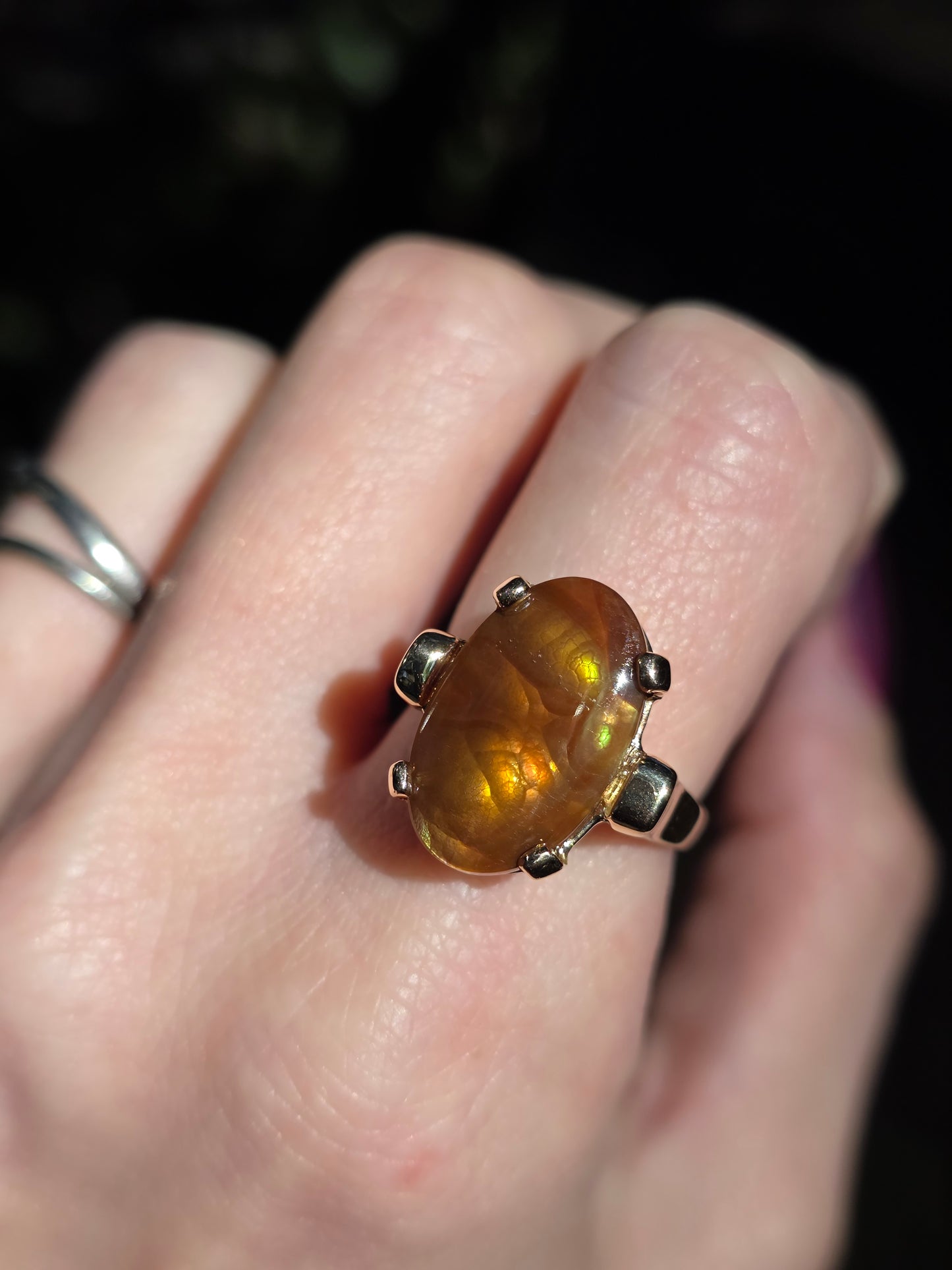 Ring with a large amber-colored stone on a person's finger against a dark background