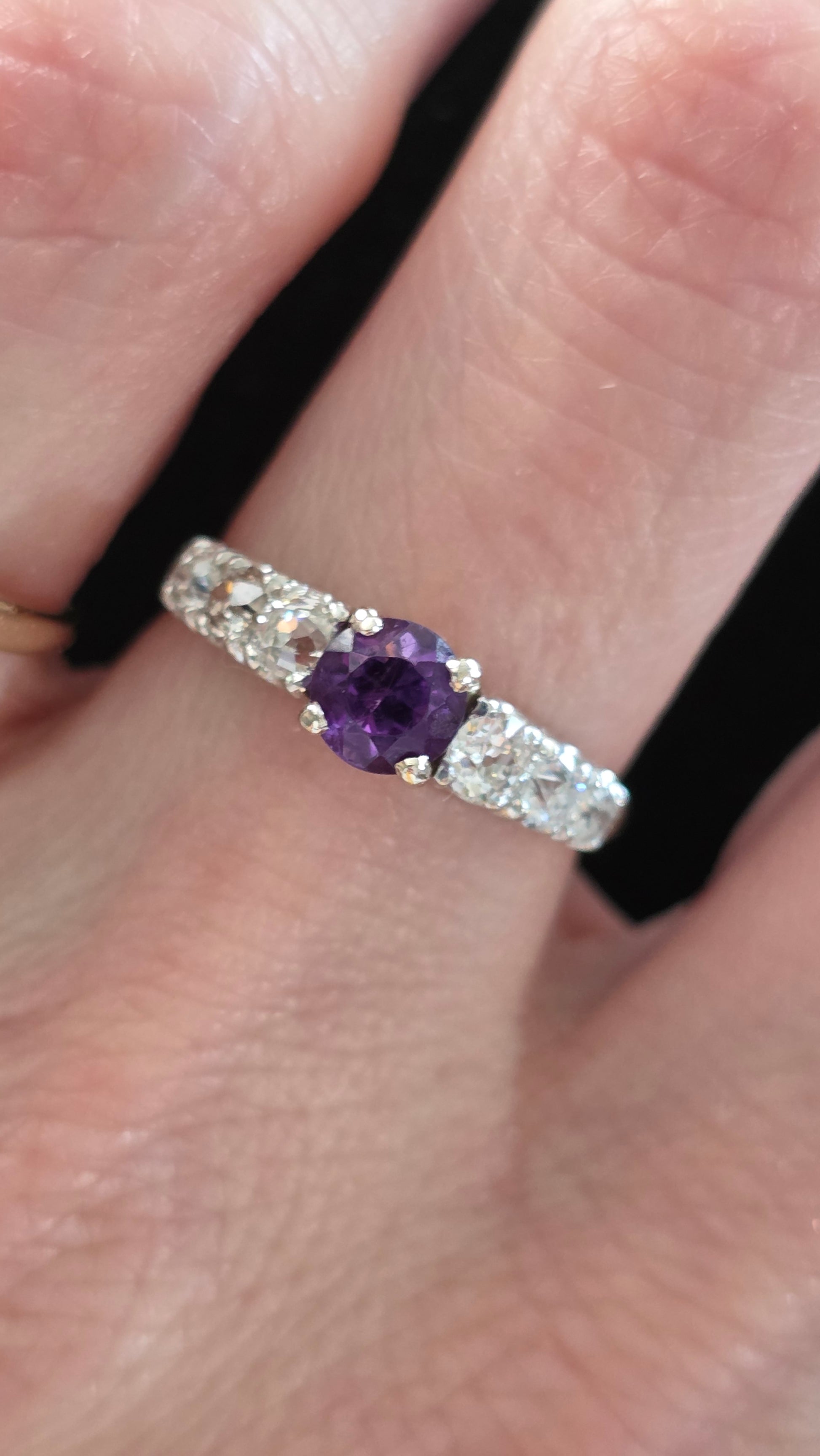 Yellow and white gold ring with a purple gemstone on a finger