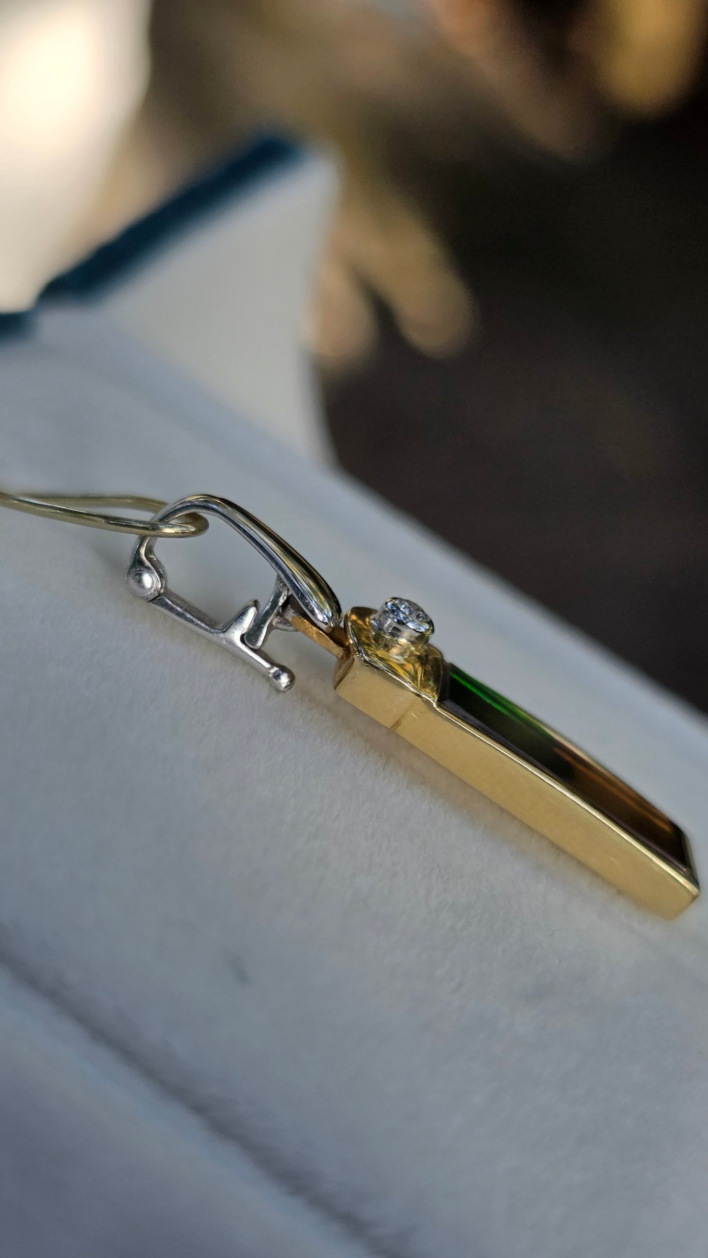 Gold necklace with a diamond pendant on a white surface