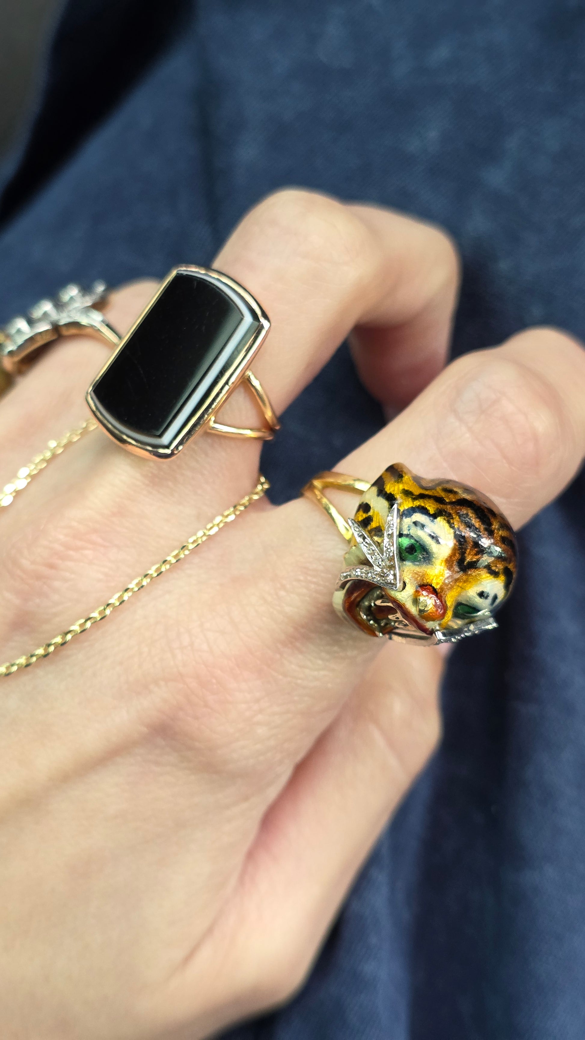Close-up of a hand wearing multiple rings with intricate designs on a dark background