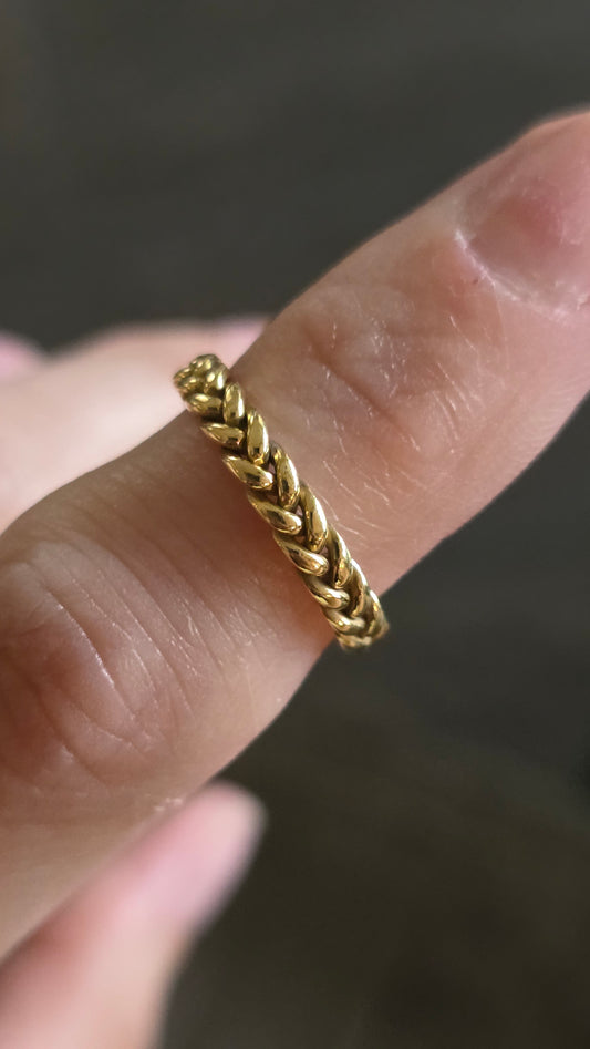 Gold braided ring on a finger with a blurred background