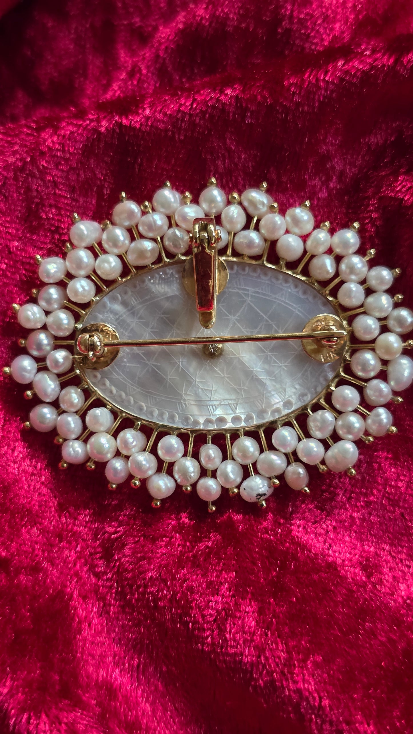Pearl-framed brooch on a red velvet background