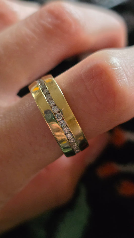 Gold ring with diamonds on a finger against a blurred background