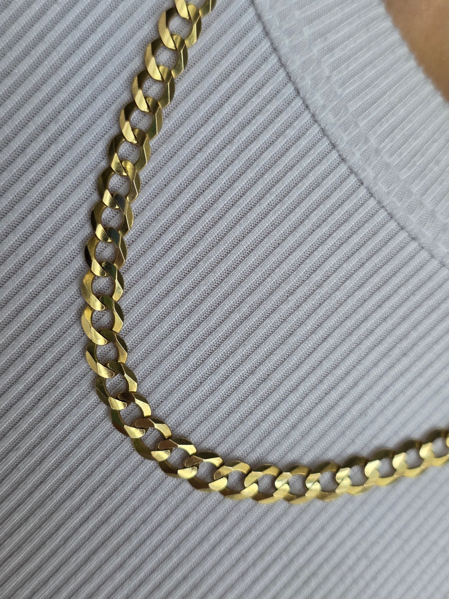Gold chain necklace on a textured gray surface