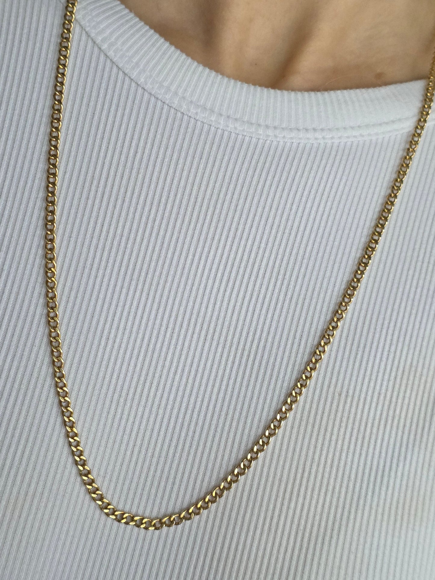Gold chain necklace on a white ribbed top