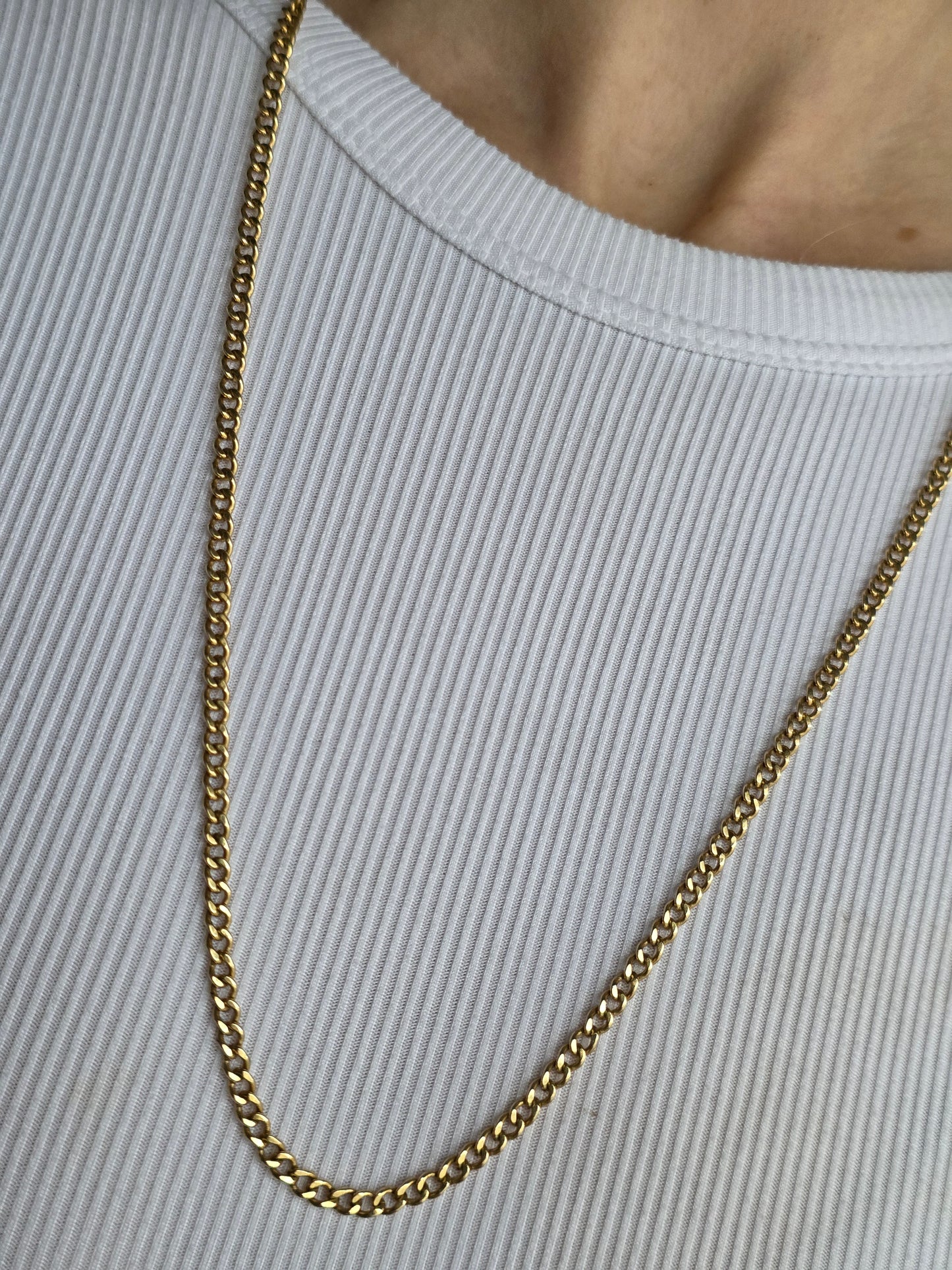 Gold chain necklace on a light gray background