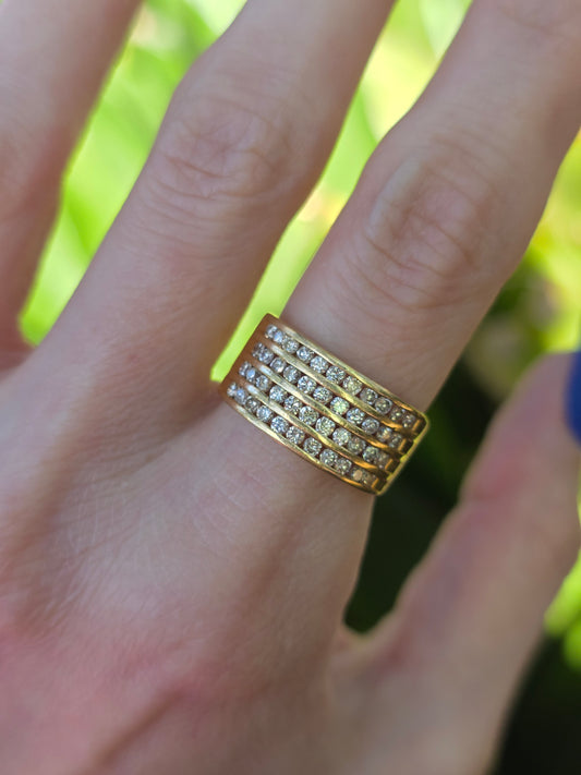 Gold ring with diamonds on a finger against a blurred green background