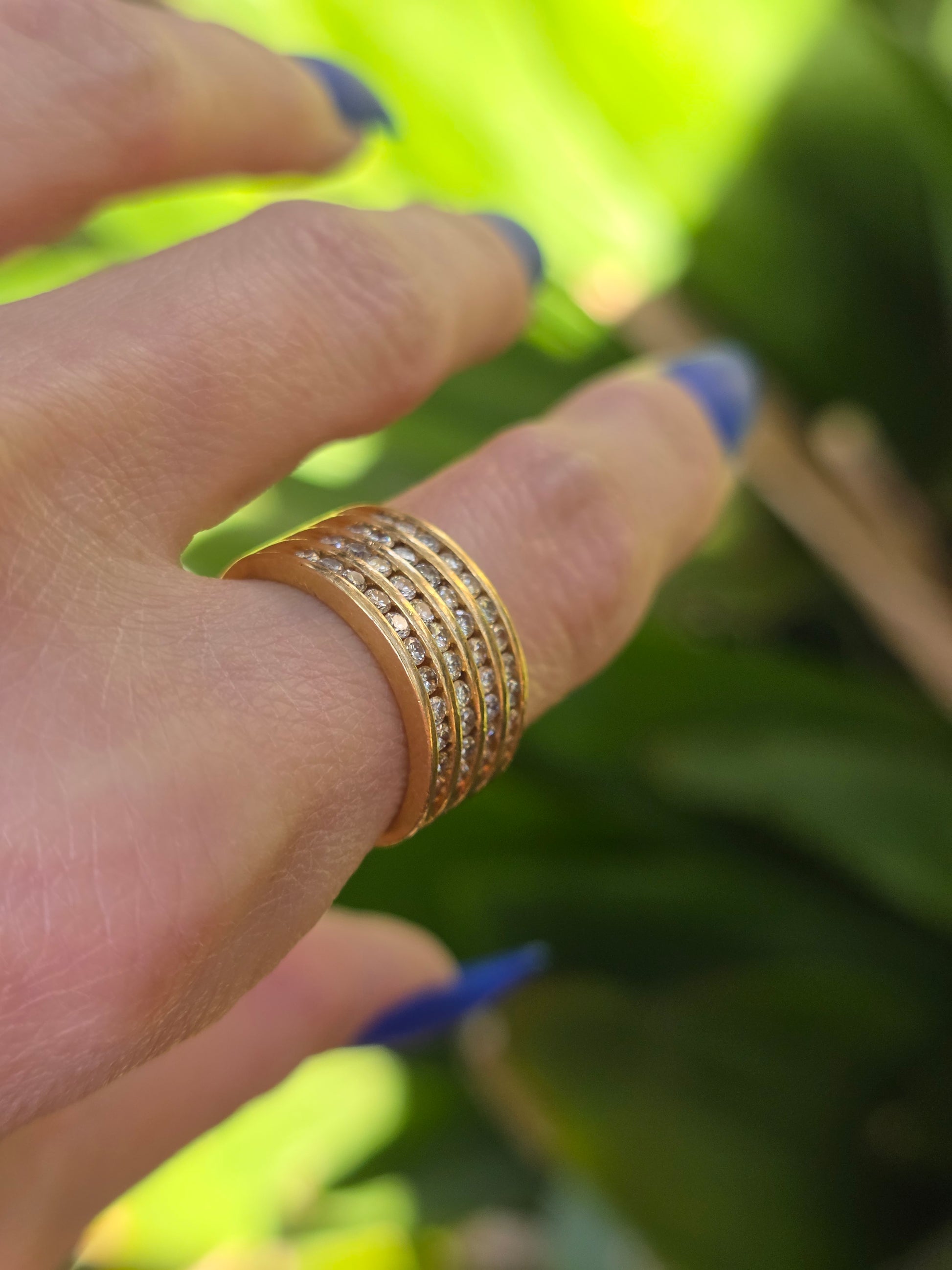 Gold ring on a finger with a blurred green background
