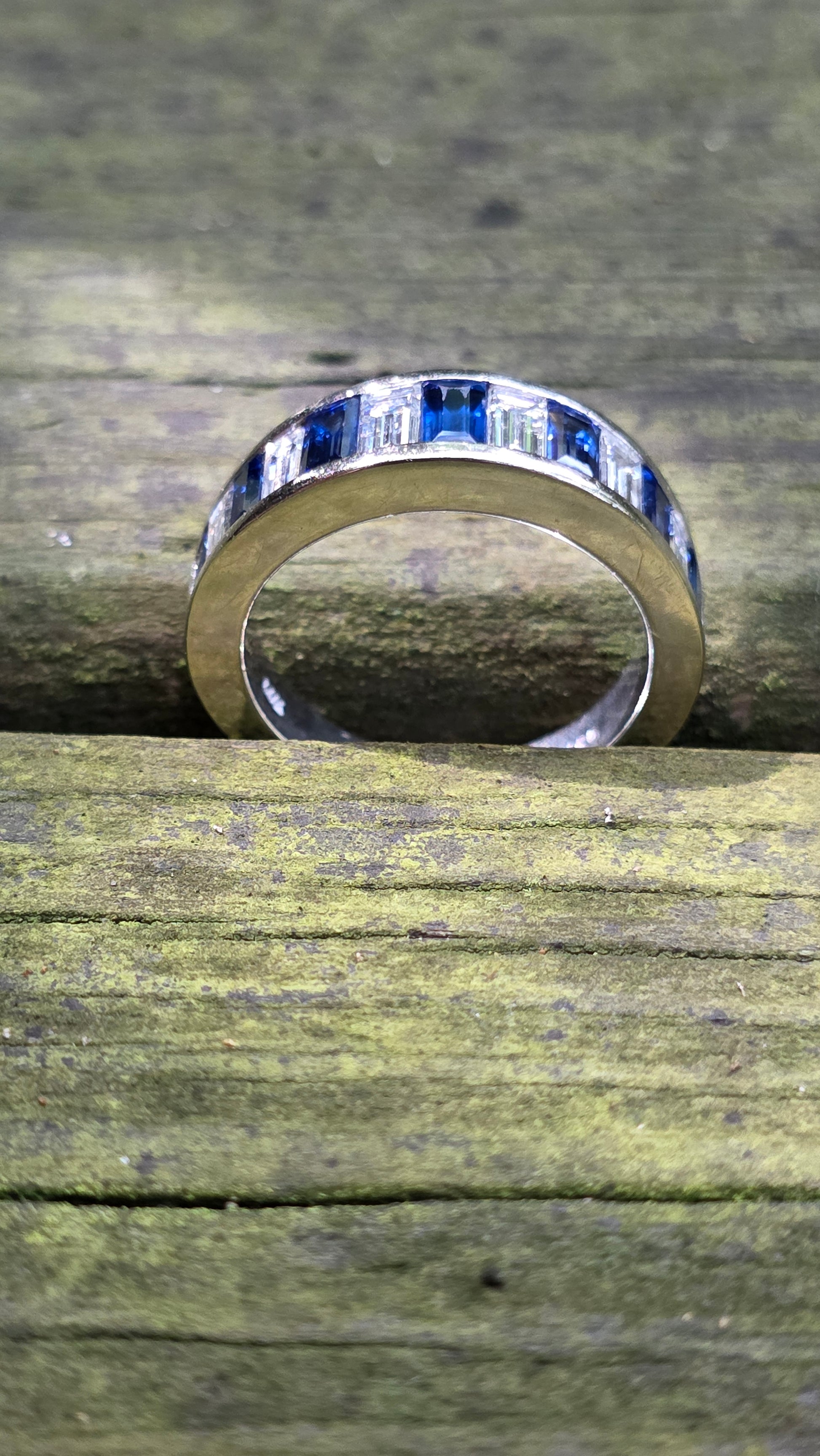 Close-up of a ring with blue and white gold design on wooden surface