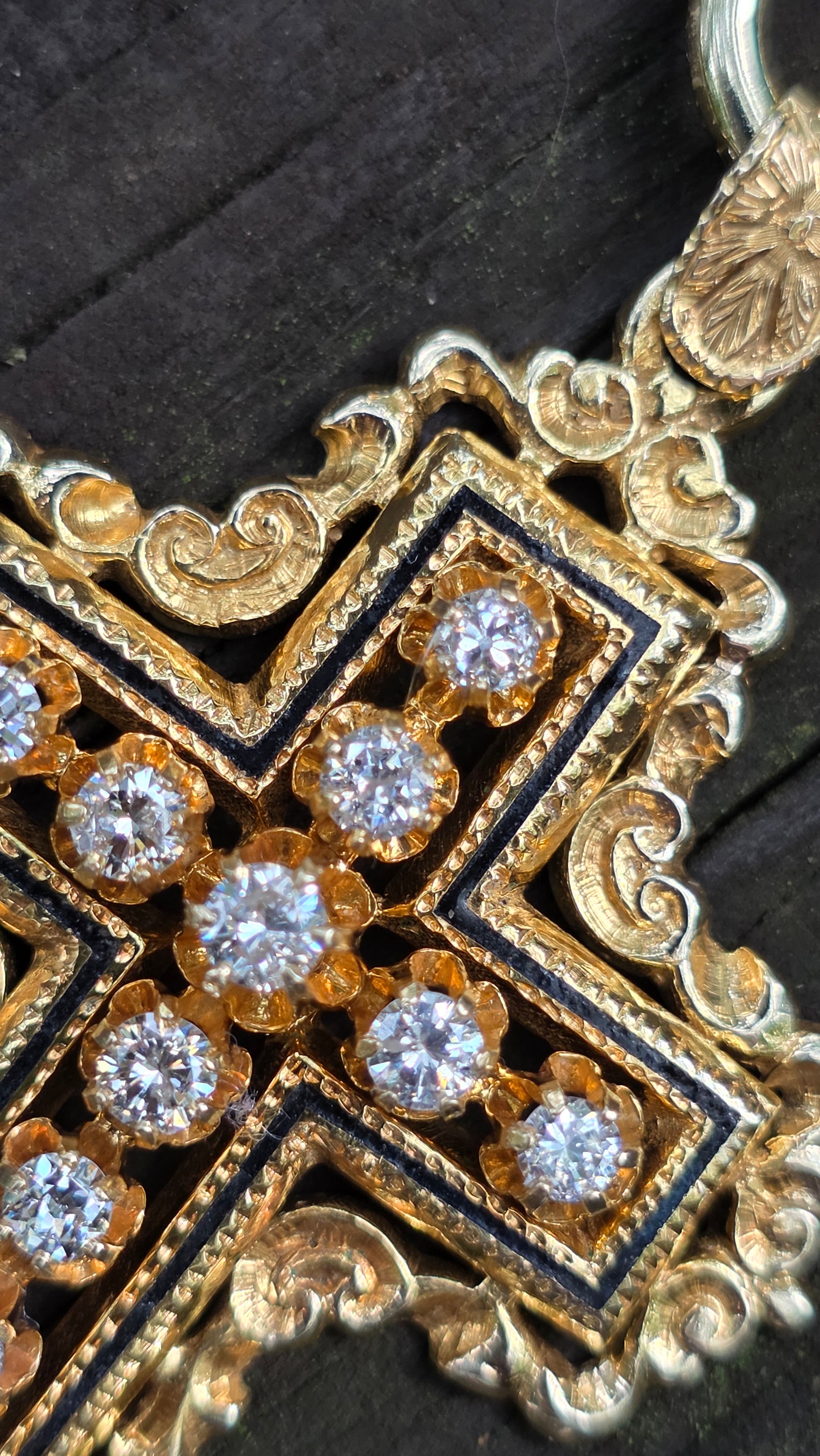 Decorative gold and black jewelry piece with embedded diamonds on a dark background