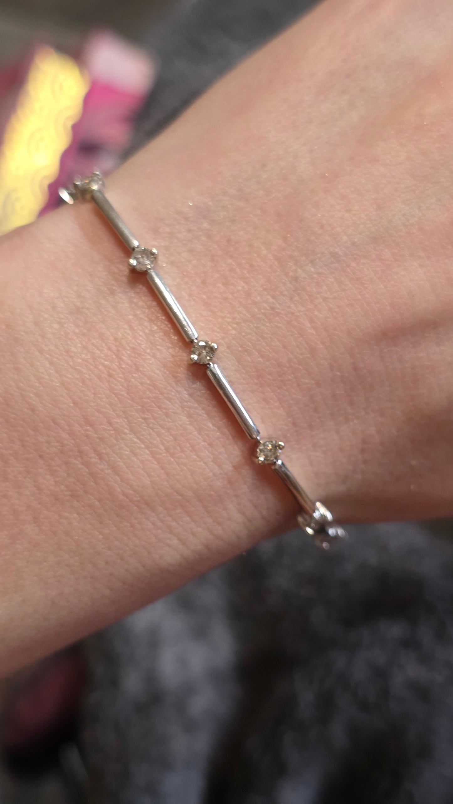 White gold and diamond bracelet on a wrist with a blurred background
