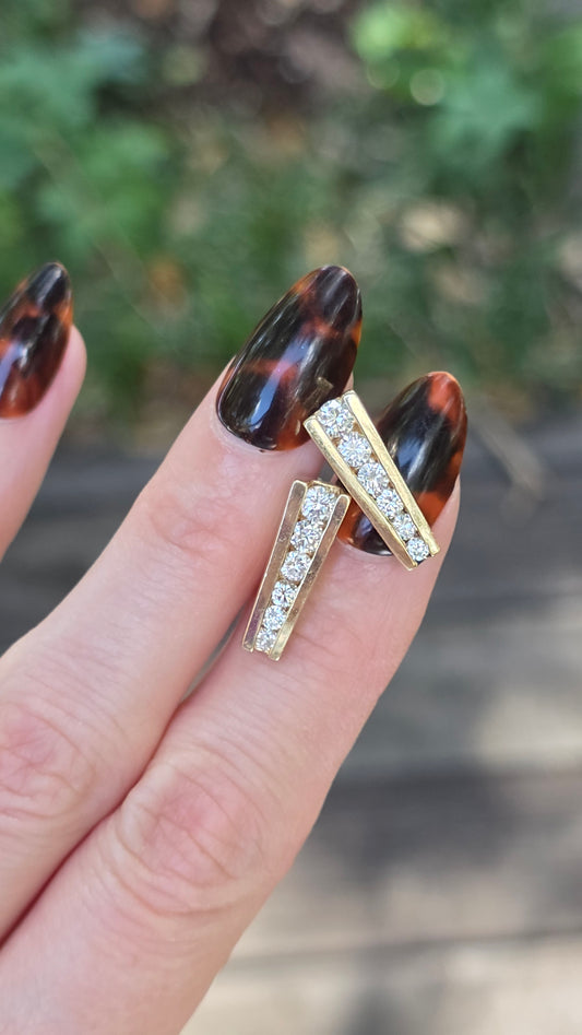 Gold ring with gemstones on a finger against a blurred natural background