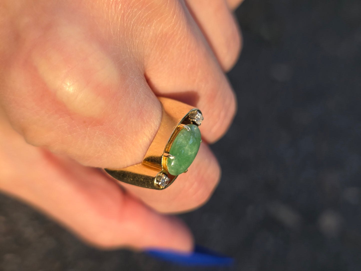 Gold ring with a green gemstone on a blurred background