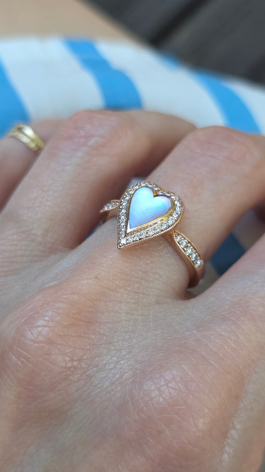 Heart-shaped ring on a person's finger with a blurred background