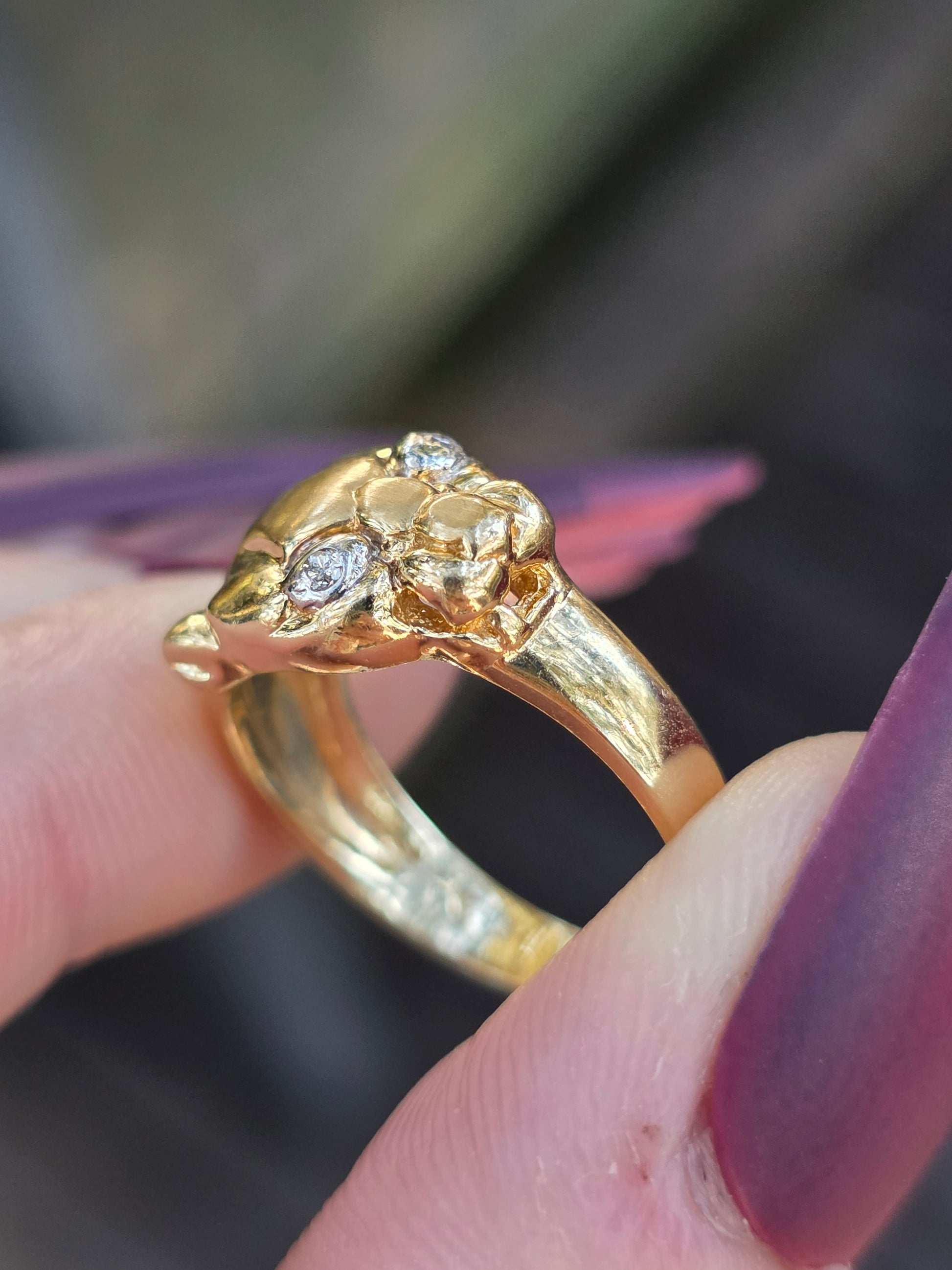 Gold ring with diamond accents held by a hand against a blurred background