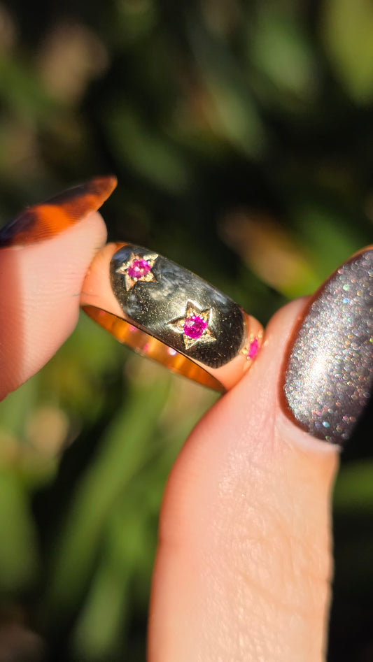 Close-up of a hand holding a ring with gemstones against a blurred green background