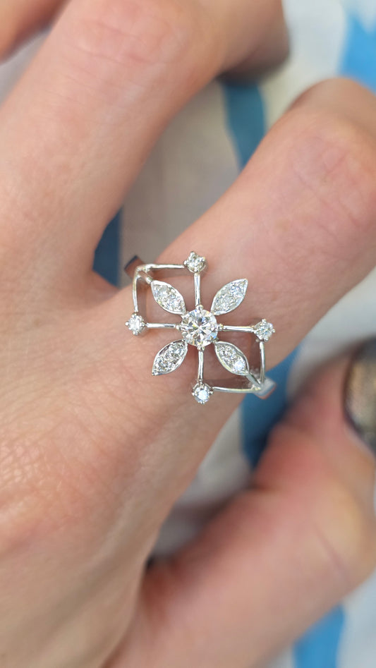 Silver ring with gemstones on a person's finger against a blurred background