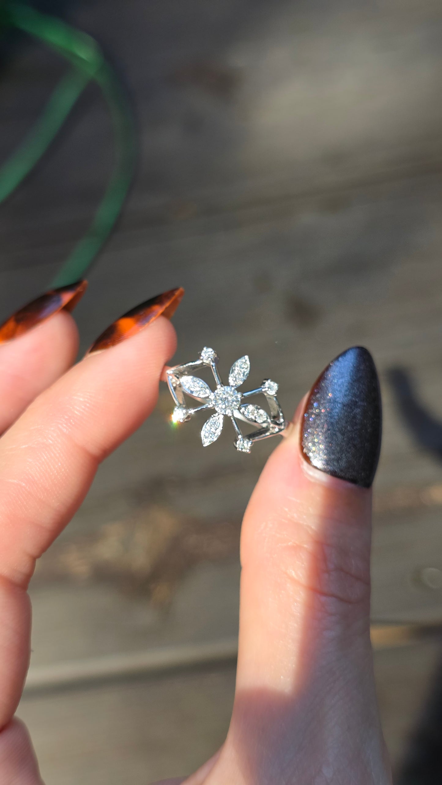 Hand holding a small silver snowflake-shaped earring with a blurred background