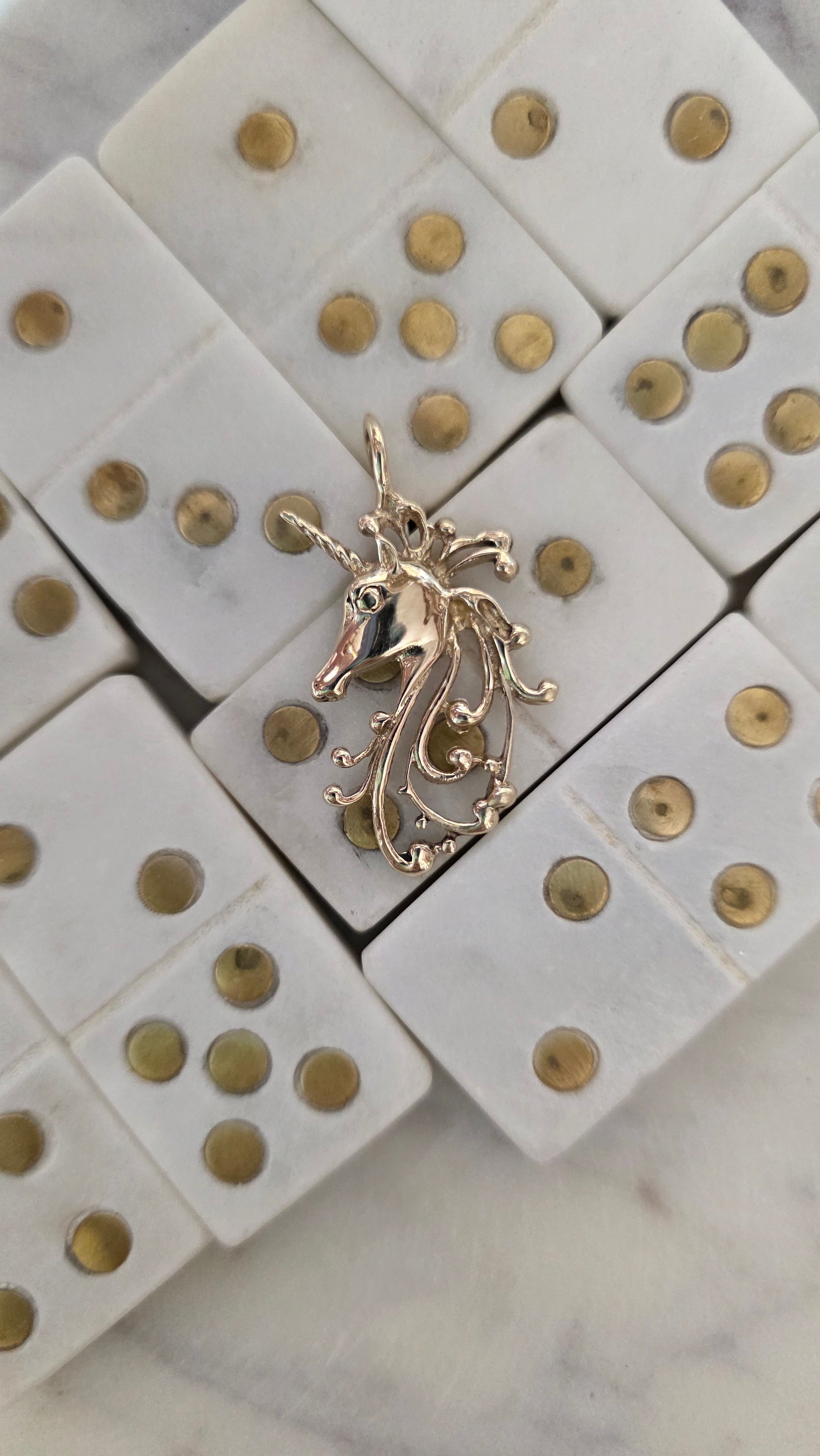 Gold Unicorn pendant on a white surface with gold accents