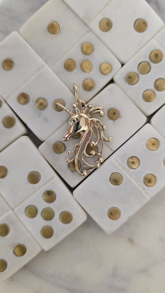 Gold Unicorn pendant on a white surface with gold accents