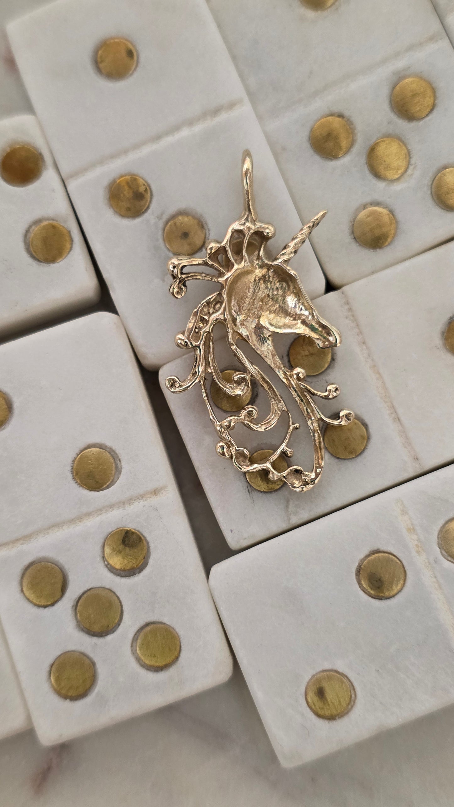 Gold pendant on a set of white dice with gold pips.