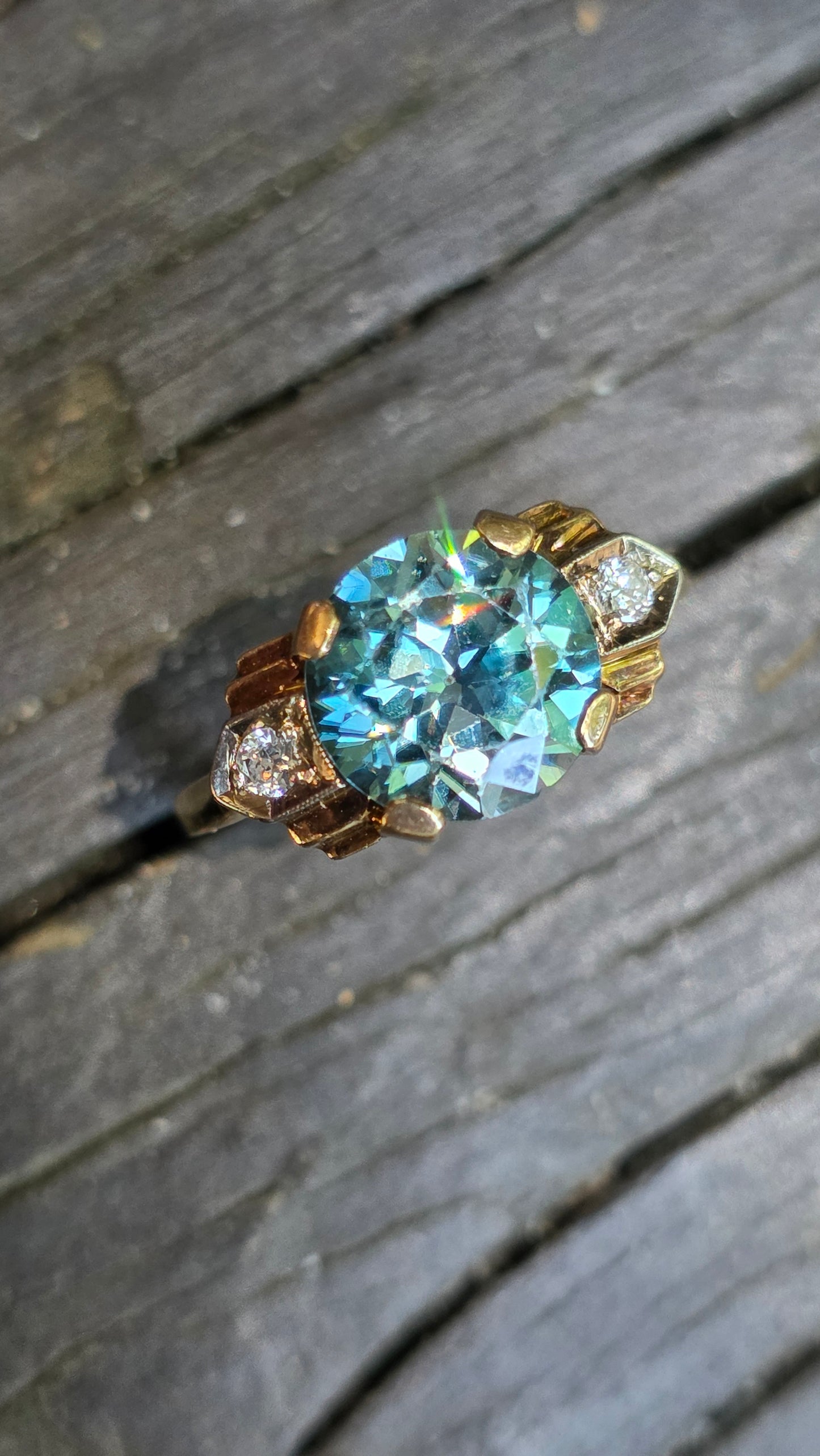 Gold ring with a large blue gemstone on a wooden surface