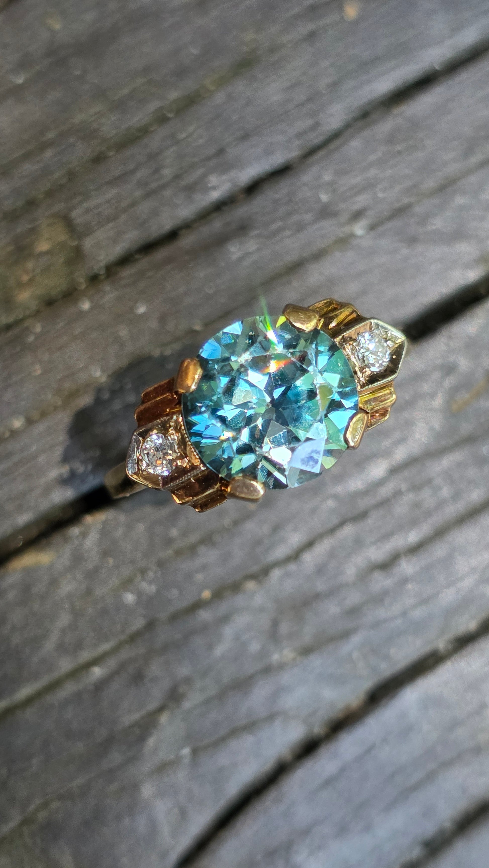 Gold ring with a large blue gemstone on a wooden surface