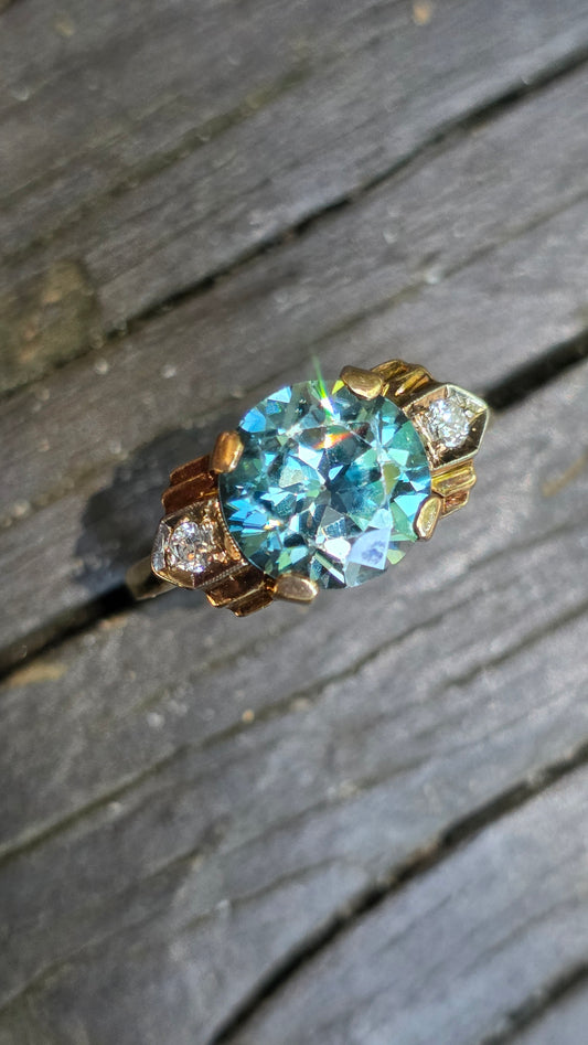 Gold ring with a large blue gemstone on a wooden surface