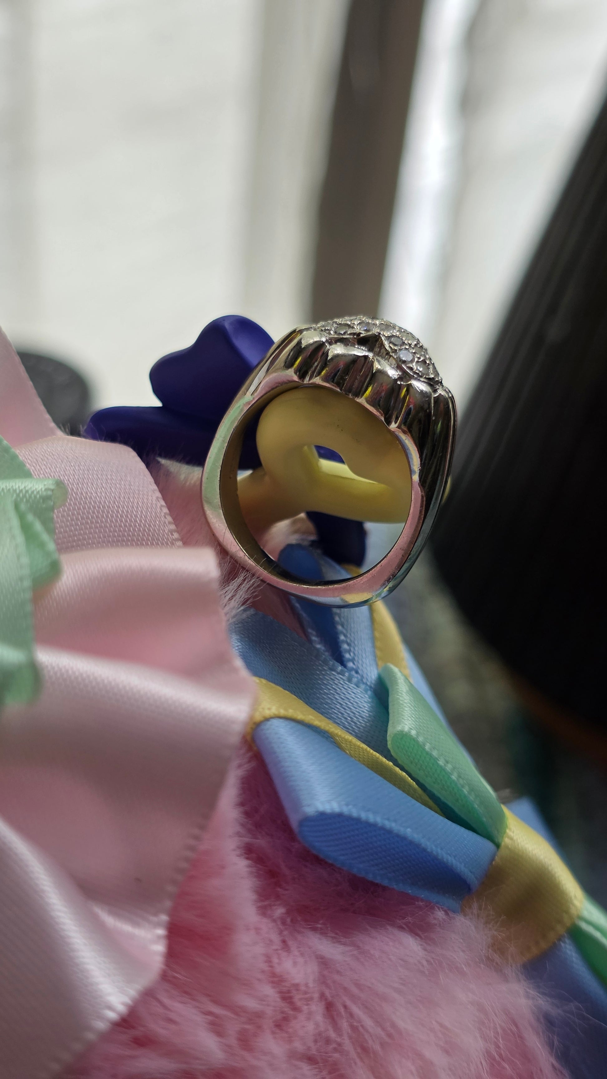 Close-up of a gold ring with a yellow center on a colorful ribbon.
